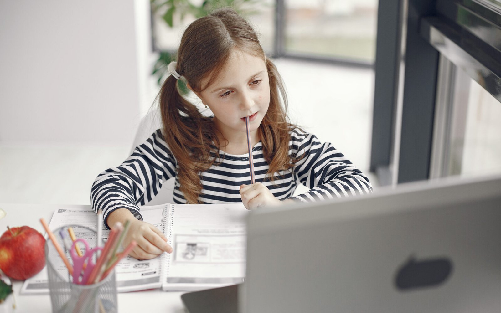 Teenager girl looking at laptop. Chiln at quarantine isolation period during pandemic. Home schooling. Social distancing. Online school test.